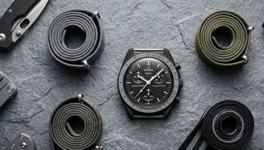 Relógio estilo Omega Swatch Moonswatch ao lado de várias pulseiras NATO coloridas de reposição.
