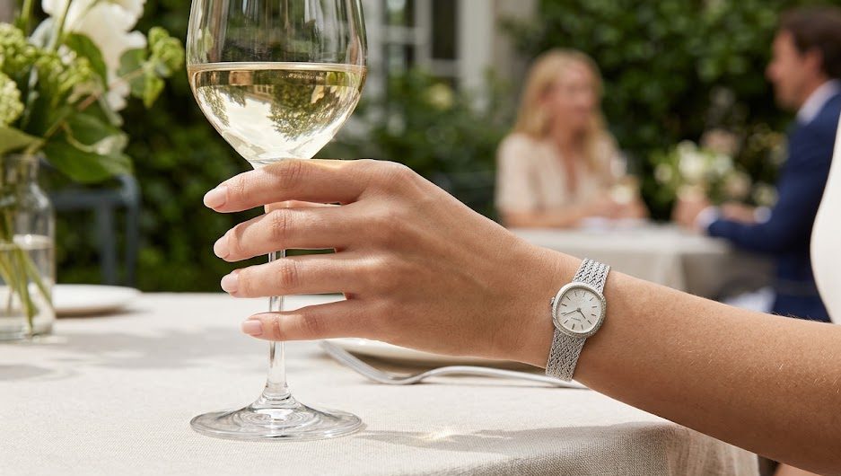 Relógio Seiko Automático Antigo Pulso de uma mulher sofisticada usando um relógio Seiko feminino antigo com pulseira delicada de aço entrelaçado, segurando uma taça de vinho.