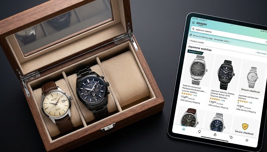 relógio Seiko solar Dois elegantes relógios japoneses, um modelo mecânico texturizado e um modelo solar, lado a lado numa caixa de luxo em cima de uma secretária com um *tablet* a mostrar a loja da Amazon.