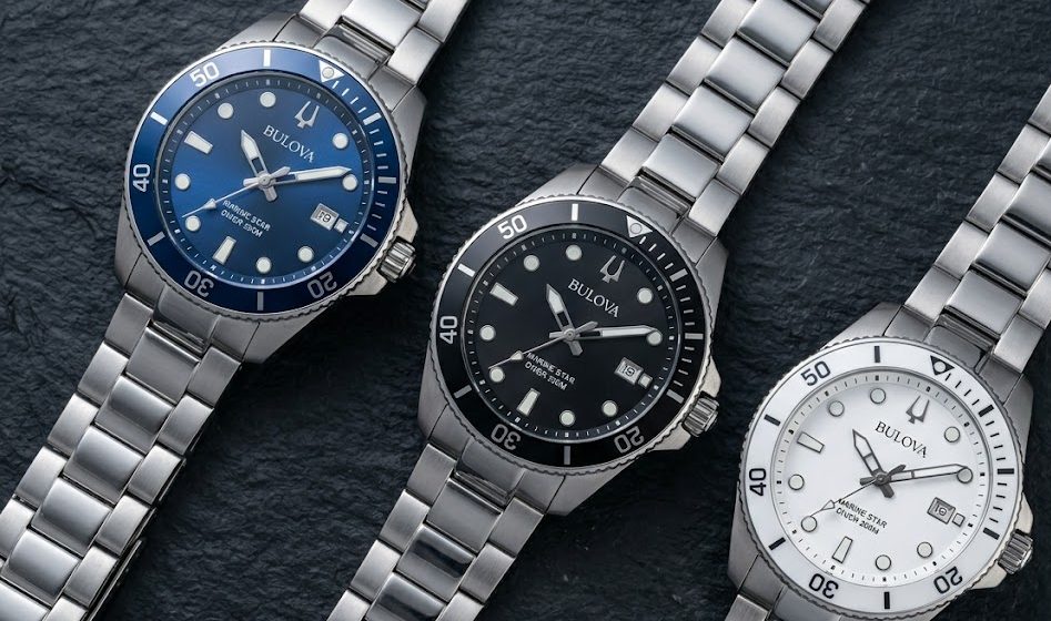 Tr&ecirc;s vers&otilde;es do Bulova Marine Star lado a lado em flat lay editorial