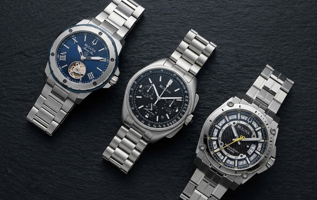 Três modelos de relógio Bulova masculino lado a lado em flat lay minimalista